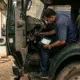 Professional Indian mechanic using a handheld truck diagnostic scanner on a heavy-duty commercial vehicle in a wor